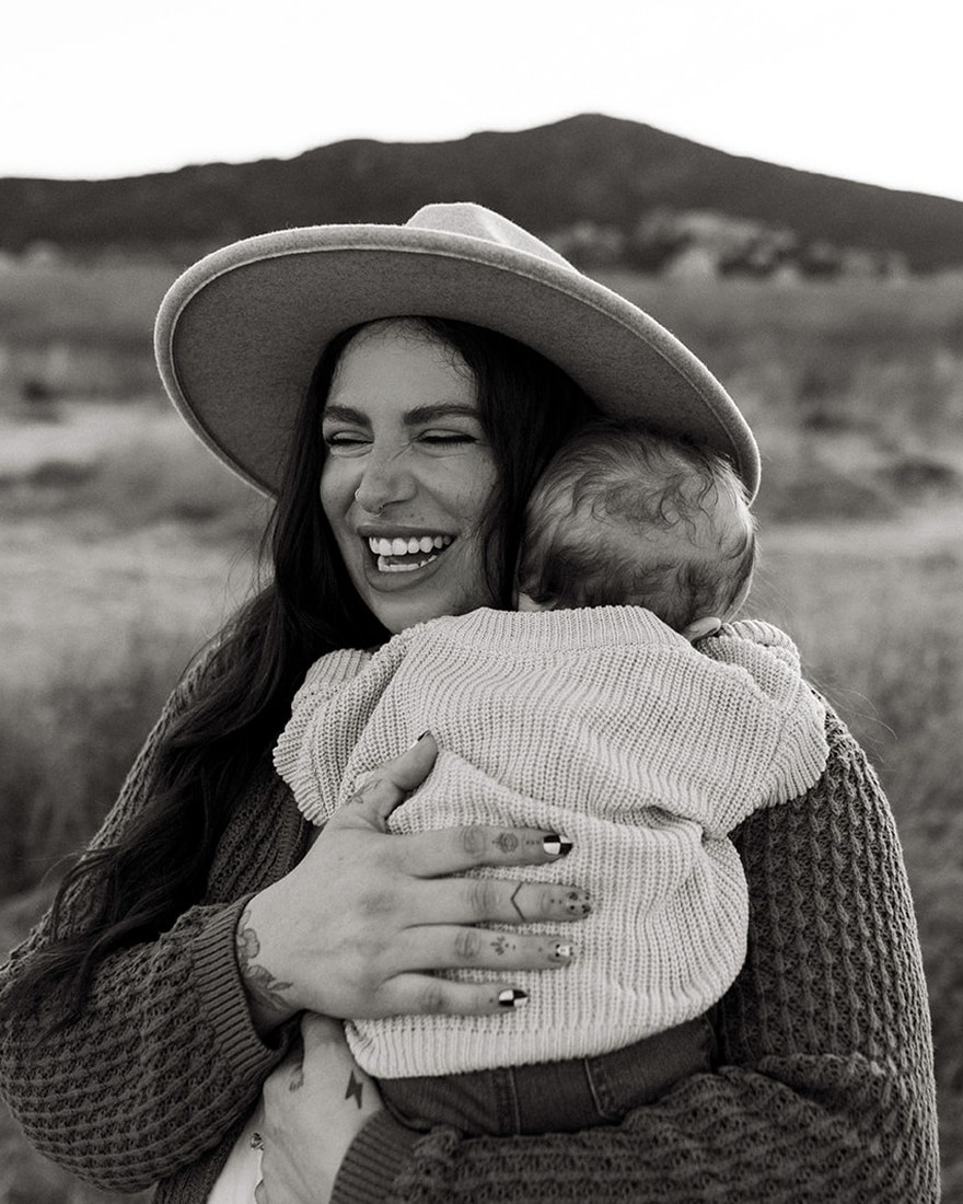 Sarah Gear laughing while holding her child outdoors